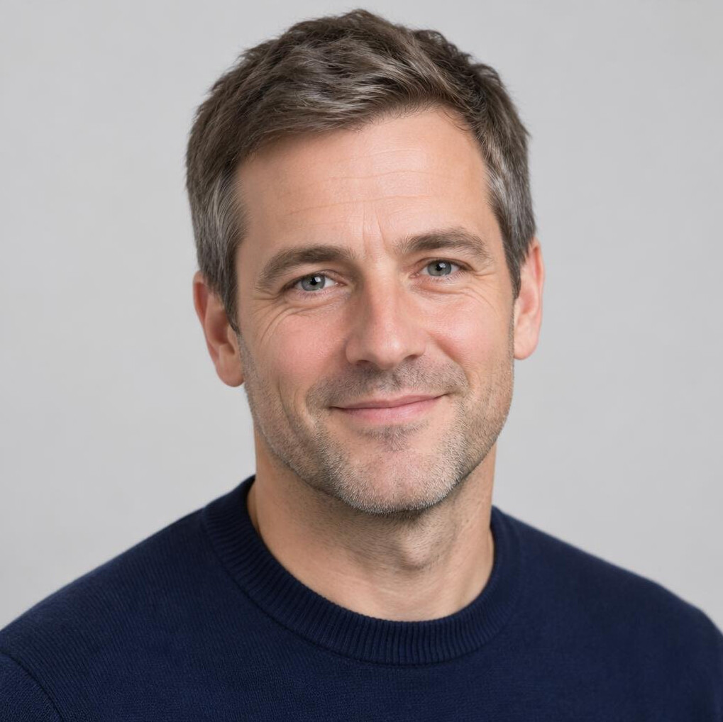 Portrait of a middle-aged man with short greying hair in a navy sweater