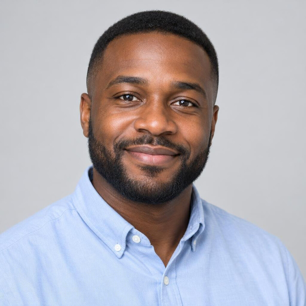 Portrait of a smiling man with short hair and a trimmed beard in a casual shirt